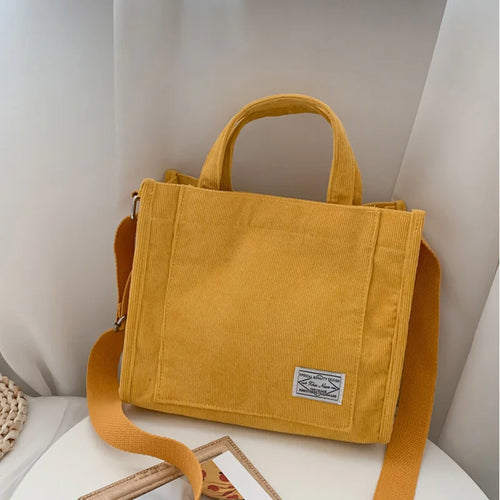 Yellow corduroy bag with a strap on a white surface